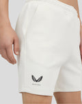 Close-up of white scuba shorts featuring a Castore logo on the lower left leg.