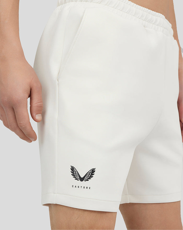 Close-up of white scuba shorts featuring a Castore logo on the lower left leg.
