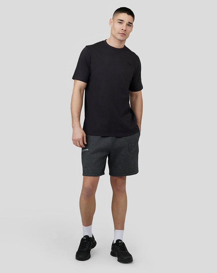 Front view of a man wearing a black short sleeve T shirt with a small embroidered logo on the left chest.