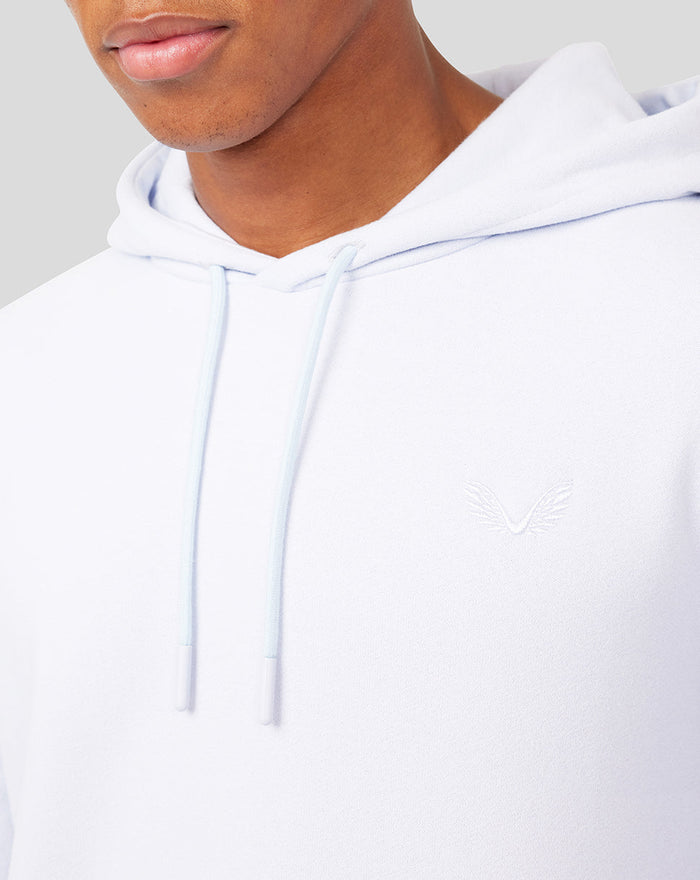 Close-up of a white hoodie showing a small embroidered chest logo and pale blue drawstrings.