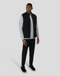 Three-quarter front view of the model in the Black Cobalt Capsule Hybrid Gilet with gray long sleeve and black joggers