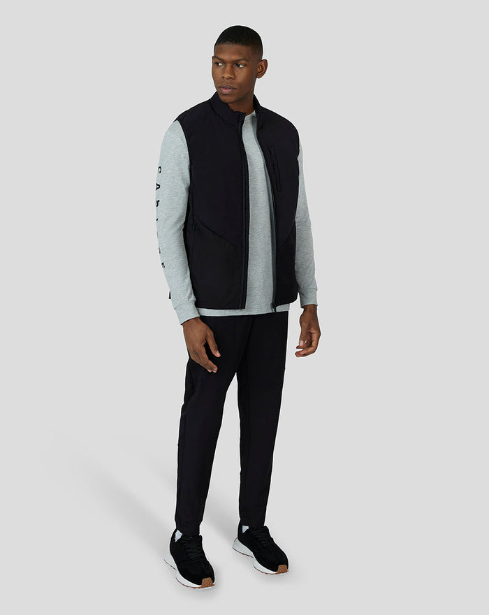 Three-quarter front view of the model in the Black Cobalt Capsule Hybrid Gilet with gray long sleeve and black joggers