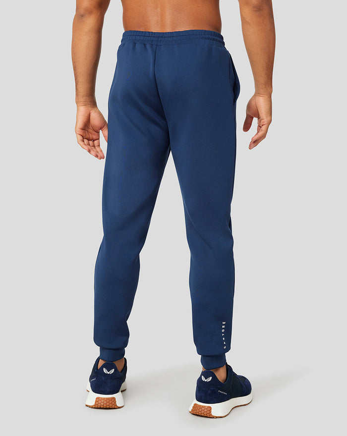 Back view of navy Peacoat Scuba Jogger with vertical Castore branding along the lower leg and navy sneakers