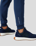 Lower leg view of navy Peacoat Scuba Jogger pants paired with navy sneakers; CASTORE branding runs down the leg.