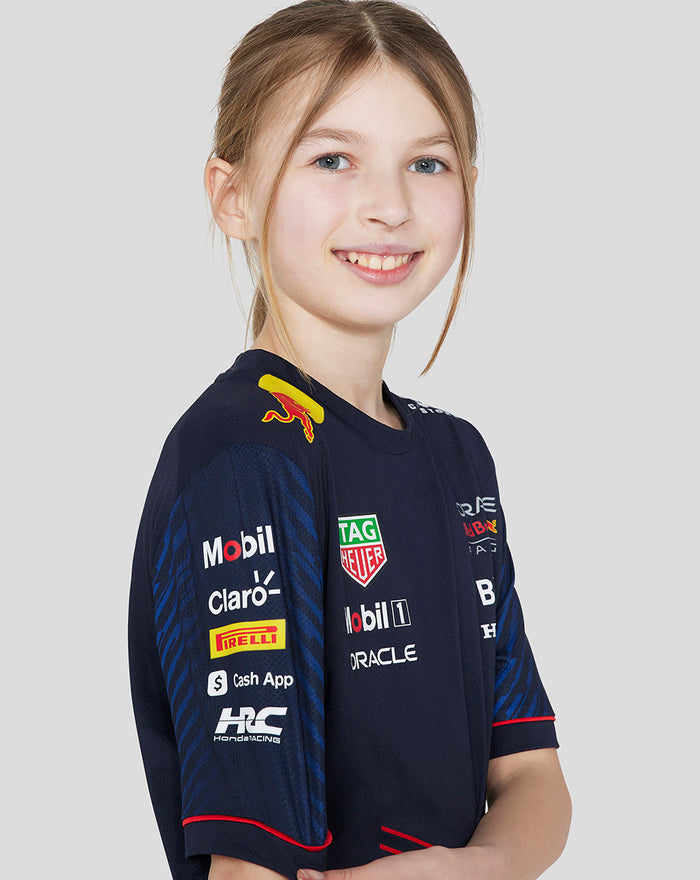 Three quarter view of a young girl wearing navy Oracle Red Bull Racing Set Up T Shirt with sponsor logos