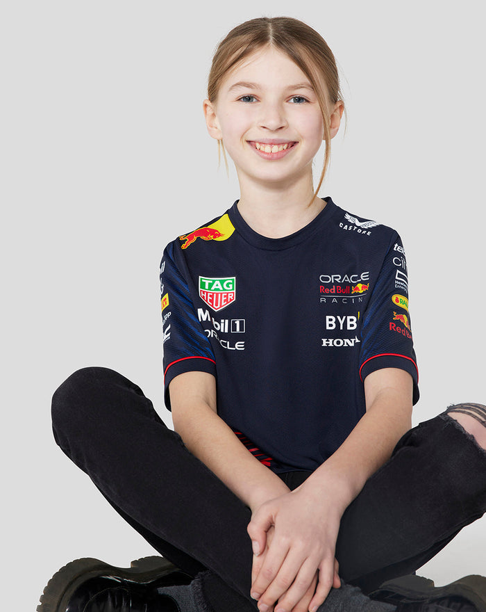 Front view of a young girl in the navy Set Up T Shirt with sponsor logos on the chest