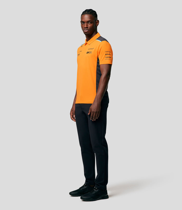 Front view of a male model in a bright orange McLaren replica polo with sponsor logos on the chest and dark side panels