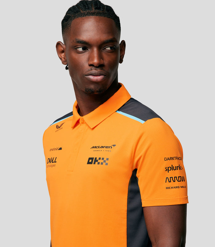 Torso shot of a man in a bright orange McLaren polo with sponsor logos on the chest