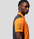 Close up portrait of a man wearing an orange Papaya and Phantom McLaren replica polo against a light gray background