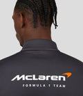 Front view of a male model in an orange McLaren replica quarter zip top with blue zipper and sponsor logos.