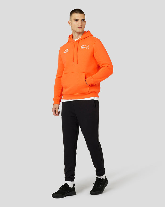 Full body shot of a model wearing the orange hoodie with Verstappen graphic on the chest, kangaroo pocket and drawcord hood